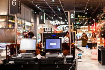 Selective focus to edge of POS machine with blurry cashier staff receive orders from customers at counter service in restaurant or cafe or department store.