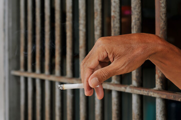 prisoner's hands behind bars with black background