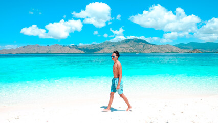Happy attractive young man on beach with white sand and indian ocean. Summer travel vacation.