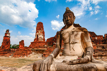 Fototapeta premium A statue of a Buddha is sitting in front of a large building