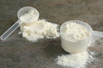 Protein powder and scoops on grey textured table
