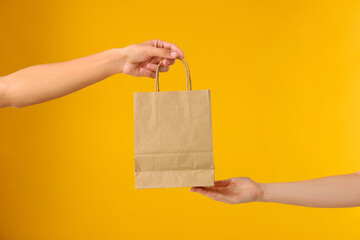 Fast-food worker giving customer's order on orange background, closeup
