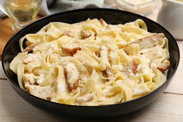 Tasty Alfredo pasta with chicken on light wooden table, closeup