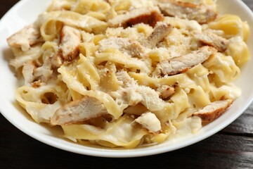 Tasty Alfredo pasta with chicken on wooden table, closeup