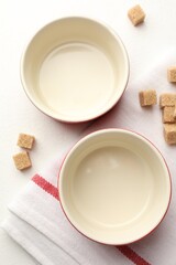 Ceramic casseroles and sugar cubes on white table, flat lay