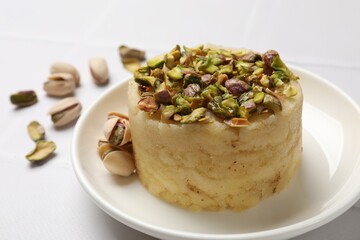 Delicious sweet semolina halva with pistachios on white tiled table, closeup