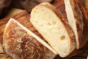 Cut loaf of fresh bread on wooden table, closeup