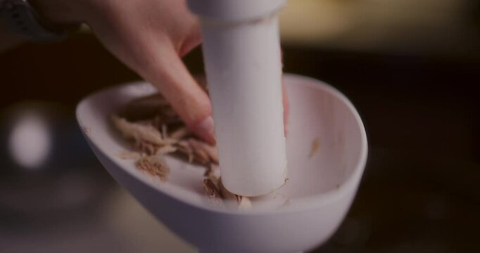Woman puts meat into a meat grinder preparing chicken pate
