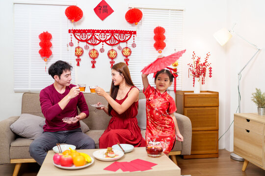 An Asian family enjoys pouring tea and spending quality time during Chinese New Year celebrations, creating a harmonious and joyful atmosphere at home