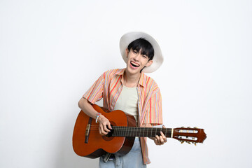 Portrait of smiling young man wearing casual striped shirt playing an acoustic guitar over white background