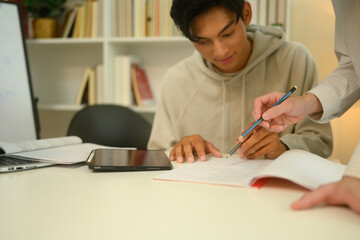 Tutor pointing to important sections in a notebook assisting a student during a study session