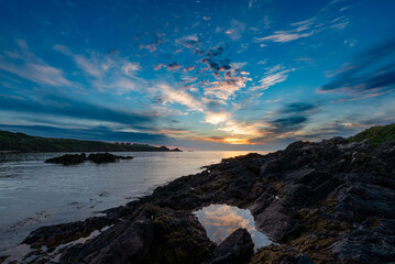 Colourful sunrise at coast reflected in rock pool