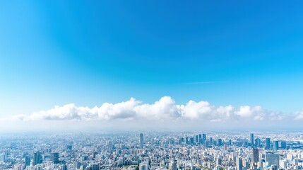 Fototapeta premium Aerial view of a sprawling modern cityscape under a clear blue sky with a line of white clouds.
