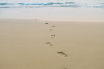 Footprints of human feet on the sand near the water on the beach.