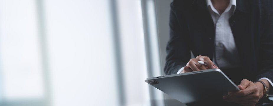 Close up, business woman using stylus pen signing e-document on digital tablet via mobile app at office, businesswoman working and surfing the internet, on digital tablet and laptop computer