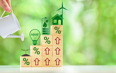Nurturing Sustainability: Investing in renewable energy and energy-efficient practices leads to significant savings and environmental benefits. A hand holding a watering can nurturing a small plant.