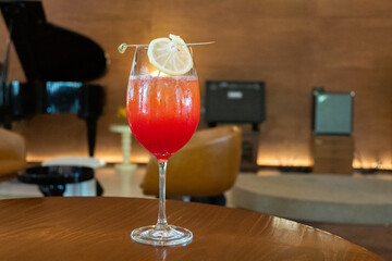 Premium Alcoholic Cocktail with blurred music band as background,Pleasant Evening In Respectable Restaurant With Cocktail,close up of wine glass on wooden table with blurry bar background scene.