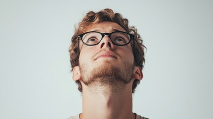 Young man looking upwards, wearing glasses, thoughtful expression, facial hair, introspective mood