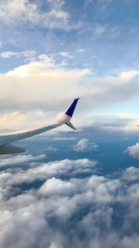 A stunning aerial view from an airplane window, showcasing a wingtip above a sea of fluffy clouds and a vibrant blue sky. The scene captures the beauty and freedom of air travel.