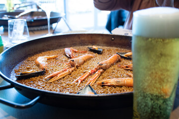 Spanish Valencian paella with traditional rice and seafood with crayfish and shrimps . seafood blurred beer