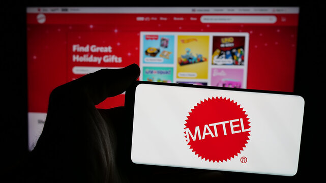 Stuttgart, Germany - 12-02-2024: Person holding mobile phone with logo of American toy company Mattel Inc. on screen in front of business web page. Focus on phone display.