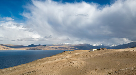 A Vast Lake Embraced by Arid Hills and Distant Snow-Capped Peaks Under a Majestic Sky