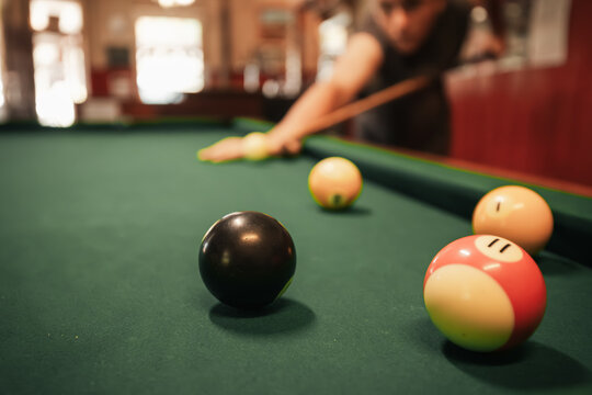 Teenage male playing 8 ball pool on billiard table in Australian pub