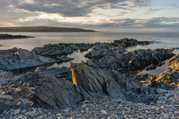 Sharp-edged rock formations by the sea near the village of Hamninberg on a calm summer evening