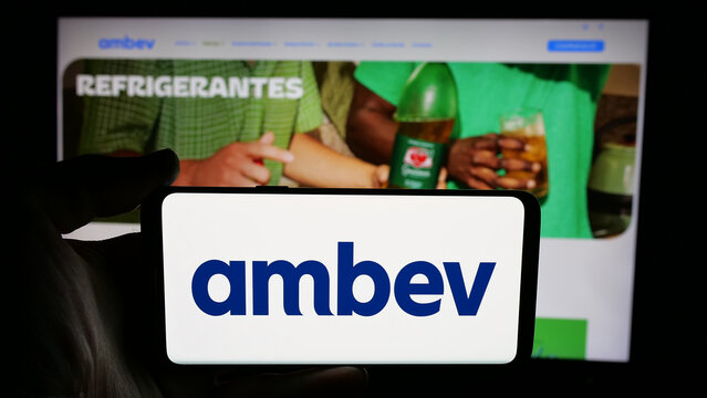 Stuttgart, Germany - 12-04-2024: Person holding cellphone with logo of Brazilian beverage company Ambev S.A. on screen in front of business webpage. Focus on phone display.