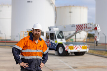 Young adult worker standing with hands on his sides on a concrete industrial site