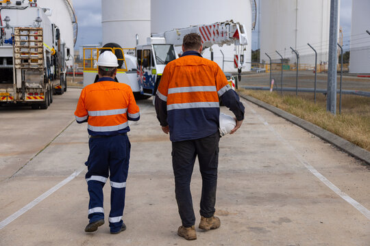 Two male workers in high visibility clothing walking towards the truck.