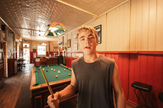 Teenage male playing 8 ball pool on billiard table in Australian pub