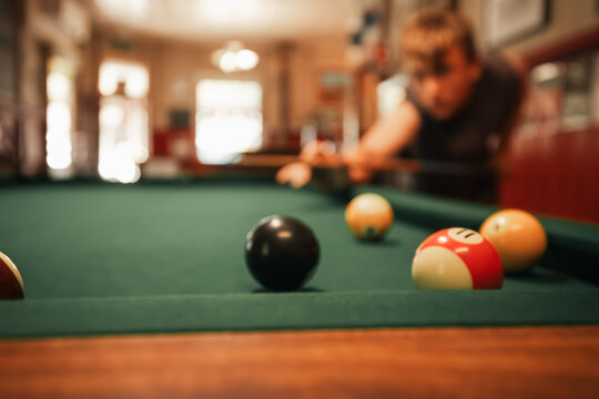 Teenage male playing 8 ball pool on billiard table in Australian pub