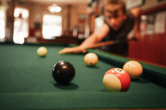 Teenage male playing 8 ball pool on billiard table in Australian pub