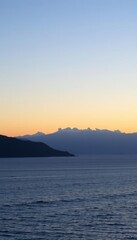 Fototapeta premium the water at sunset with mountains in the background