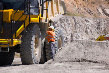 Man in high visibility clothes checking the sides of the dump truck.