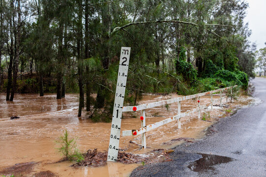 Depth meter beside bridge over creek that is almost underwater in flood