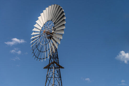 Traditional windmill set against a clear blue sky with a few clouds.