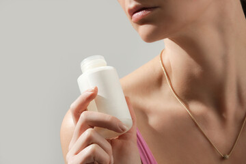 Close up of woman holding bottle with skincare cosmetic product	