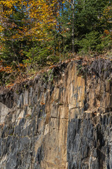 Karachay-Cherkessia. Dombay. At foot of mountains, on steep cliffs, pine and spruce trees grow. Evergreen plants create beauty of mountain landscape. Sunny day. Autumn 2024.