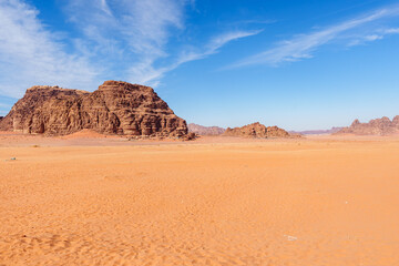 Fototapeta premium Scenic view of Wadi Rum Desert in Jordan. Landscape with Rocky Formation Under Blue Sky and Wispy Clouds..