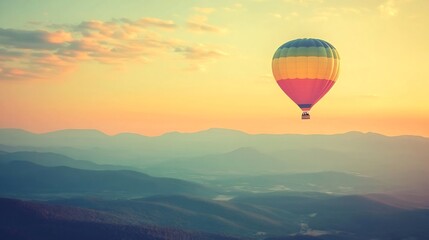 Obraz premium Hot Air Balloon Soaring Over Majestic Mountains at Sunrise