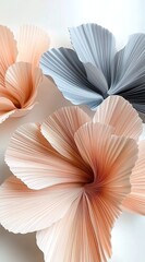 Gigantic pleated flowers made of paper, in a peach and grey color palette, against a white background