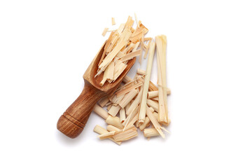 A wooden scoop filled with organic Lemongrass (Cymbopogon flexuosus), placed beside a heap of lemongrass , isolated on a white background.