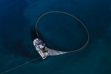 A bird's eye view of a large fishing vessel retrieving its nets. 