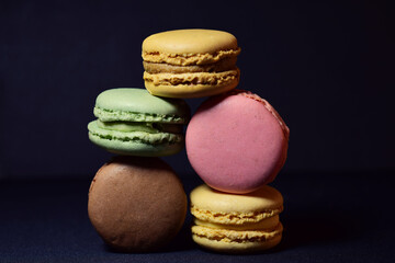 Colorful macarons stacked, isolated, on black background and copy space.	