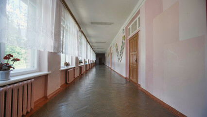 Walking down a long. Empty school corridor on the last day of school. Sunlight streams through windows. Casting a warm glow on wood floors and walls. Creating a calm