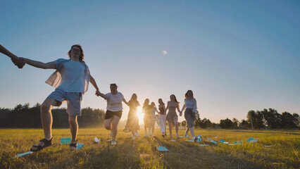 Joyful high school graduates running together in a field at sunset, rejoicing in their accomplishments and newfound freedom
