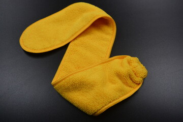 An unusual cleaning cloth, a long yellow microfiber set on a black, matte plastic background.