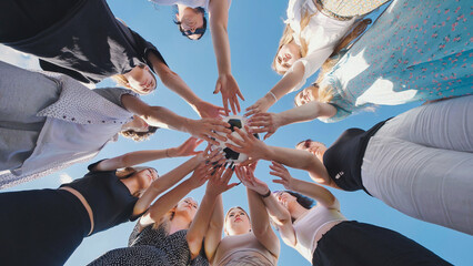 Group of high school girls forming a circle, holding a soccer ball together, symbolizing teamwork...